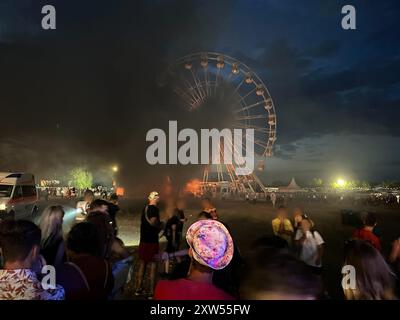 17 août 2024, Saxe, Großpösna : les visiteurs du Highfield Festival regardent une grande roue sur laquelle des flammes peuvent être aperçues. Un incendie s'est déclaré sur une grande roue au Highfield Festival sur le lac Störmthal. Photo : Str./dpa - ATTENTION : personne(s) a/ont été pixélisée(s) pour des raisons légales Banque D'Images