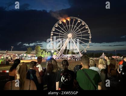 17 août 2024, Saxe, Großpösna : les visiteurs du Highfield Festival regardent une grande roue sur laquelle des flammes peuvent être aperçues. Un incendie s'est déclaré sur une grande roue au Highfield Festival sur le lac Störmthal. Photo : Str./dpa Banque D'Images