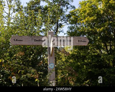 EAST BERGHOLT, SUFFOLK, Royaume-Uni - 29 JUILLET 2024 : panneau en bois avec indications pour Flatford Mill et Dedham Banque D'Images