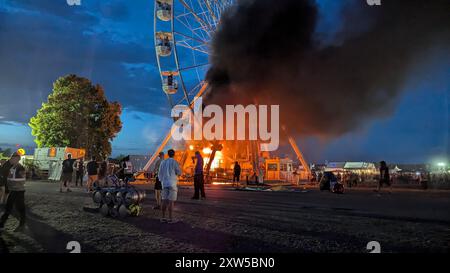 17 août 2024, Saxe, Großpösna : les visiteurs du Highfield Festival regardent une grande roue sur laquelle des flammes peuvent être aperçues. Un incendie a éclaté sur une grande roue au Highfield Festival sur le lac Störmthal. Environ 30 personnes ont été blessées. Photo : -/spm-gruppe/dpa Banque D'Images