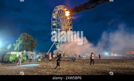 17 août 2024, Saxe, Großpösna : les visiteurs du Highfield Festival et les assistants regardent une grande roue sur laquelle des flammes peuvent être aperçues. Un incendie a éclaté sur une grande roue au Highfield Festival sur le lac Störmthal. Environ 30 personnes ont été blessées. Photo : -/spm-gruppe/dpa Banque D'Images