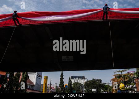 Bandung, Indonésie. 17 août 2024. Les pompiers descendent d'un pont pour hisser un drapeau rouge et blanc géant lors d'un salut de trois minutes commémorant le 79e jour de l'indépendance de la République d'Indonésie à Bandung. (Photo de Dimas Rachmatsyah/Pacific Press) crédit : Pacific Press Media production Corp./Alamy Live News Banque D'Images