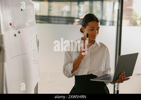 Une femme professionnelle activement engagée dans la présentation tout en utilisant son ordinateur portable Banque D'Images