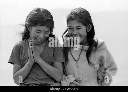 Deux sœurs riantes donnent le salut Namaste dans les collines moyennes du Népal sur le trek du sanctuaire Annapurna - Népal 1988 Banque D'Images