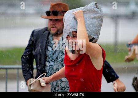 Une fan de course se protège de la pluie au Woodbine Racetrack à Toronto, Canada, le 17 août 2024. La première course de pur-sang du Canada, la King's plate, est annulée pour des raisons de sécurité des chevaux en raison des précipitations excessives sur les surfaces des pistes. (Photo de Mike Campbell/NurPhoto) crédit : NurPhoto SRL/Alamy Live News Banque D'Images