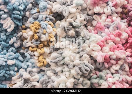 Fil peluche moelleux dans le stockage. Fond coloré de fil bouffé. Passe-temps de tricot. Rangée de fils de différentes couleurs. Magasin de main-d'œuvre. Arrière-plan tricoté. Banque D'Images