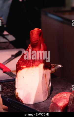 Gros morceau de jambon avec des tranches coupées sur un plateau en bois. Viande dans un restaurant. Comptoir de boucherie. Banque D'Images