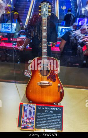 Guitare exposée au Hard Rock Cafe de Manhattan, avec John Lennon et Bob Dylan, avec plaque détaillant l'histoire de Gibson G-160E Acoustic 1966. Banque D'Images