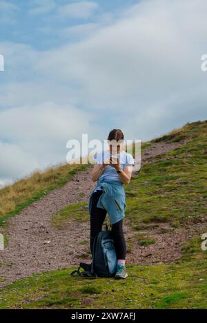 Femme utilisant un smartphone sur la randonnée en plein air, Écosse Banque D'Images