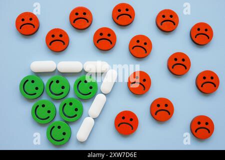 Visages souriants heureux séparés des tristes par des pilules antidépresseurs, symbolisant la santé mentale. Banque D'Images