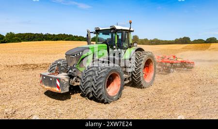 Tracteur avec pneus jumelés et cultivateur au travail dans le champ après la récolte des céréales - N° 2020 Banque D'Images