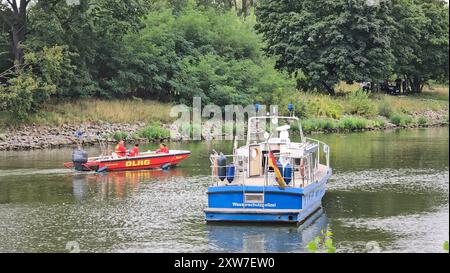 Brandenburg an Der Havel, Allemagne. 18 août 2024. À Brandebourg/Havel, des bateaux de la police des eaux et du DLRG naviguent le long du Silokanal après qu'un corps ait été trouvé ici. Il n'est pas clair s'il s'agit d'un crime. Selon un article paru dans le journal 'Märkische Allgemeine', le corps sans vie flotte toujours dans l'eau. La police a bouclé la banque du Silokanal. Crédit : Cevin Dettlaff/dpa/Alamy Live News Banque D'Images