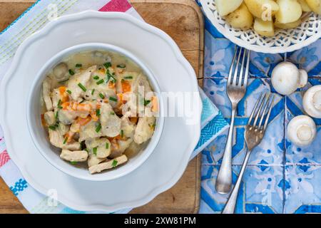 Porc dans une sauce crémeuse aux champignons avec des jeunes pommes de terre bouillies Banque D'Images