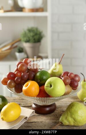 Vase en verre avec différents fruits frais sur une table en bois Banque D'Images