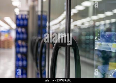 Poignée noire élégante d'une porte de réfrigérateur dans une épicerie - produits flous en arrière-plan. Prise à Toronto, Canada. Banque D'Images