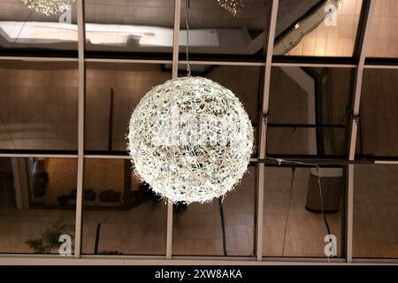 Sphère de lumière blanche complexe suspendue projette une douce lueur dans un espace intérieur moderne. Prise à Toronto, Canada. Banque D'Images