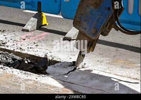 Londres, Angleterre, Royaume-Uni - 21 juin 2022 : excavatrice avec un accessoire de forage pneumatique utilisée pour briser la surface de la route d'une rue dans le centre de Londres Banque D'Images