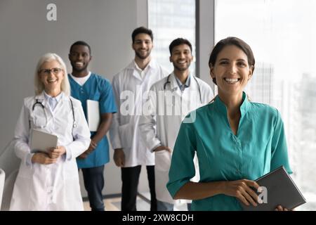 Belle femme hispanique interniste en tenue médicale posant avec des collègues Banque D'Images