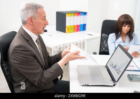 Homme d'affaires en colère se plaignant sur un document lors d'une réunion, mauvais concept de qualité de travail Banque D'Images