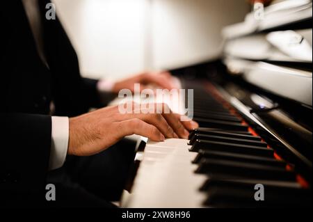 Capturer les mains d'un pianiste passionné jouant du clavier, mettant en valeur l'émotion et la musicalité. Élégance sur scène avec des touches noires et blanches. Parfait f Banque D'Images