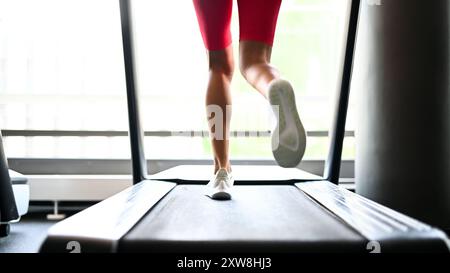 Détail des jambes d'une femme qui court sur un tapis roulant dans une salle de gym Banque D'Images