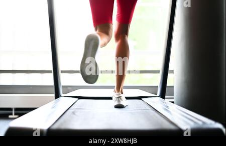 Détail des jambes d'une femme qui court sur un tapis roulant dans une salle de gym Banque D'Images