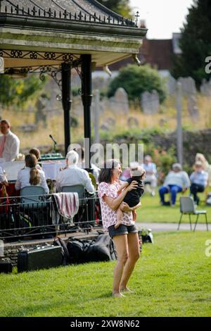 Les Burys, Godalming. 18 août 2024. Un après-midi chaud et ensoleillé pour les Home Counties. Les gens apprécient la musique dans le parc au Godalming Bandstand dans le Surrey. Tous les dimanches après-midi pendant les mois d'été, de la musique live est jouée avec une variété de genres couverts. Cet après-midi, c'était le tour de 'The Band of the Surrey Yeomanry', parrainé par BL Vision de Farncombe. Crédit : james jagger/Alamy Live News Banque D'Images