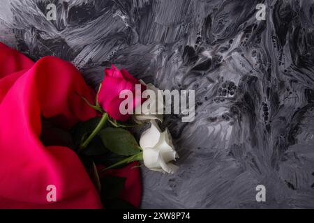 Roses blanches et roses sur texture monochrome abstraite avec tissu rouge vif. Banque D'Images