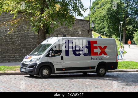 Tallinn, Estonie - 19 juillet 2023 : une camionnette FedEx garée dans une rue historique d'Estonie, prête pour la livraison de colis *** Ein FedEx-Lieferwagen parkt in einer historischen Straße in Estland, bereit für die Paketzustellung Banque D'Images