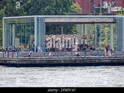 Jane’s Carousel se tient à l’ombre du pont de Brooklyn. L'amusement vitré a été déplacé de Youngstown, Ohio. Vue depuis le ferry East River. Banque D'Images