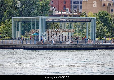 Jane’s Carousel se tient à l’ombre du pont de Brooklyn. L'amusement vitré a été déplacé de Youngstown, Ohio. Vue depuis le ferry East River. Banque D'Images