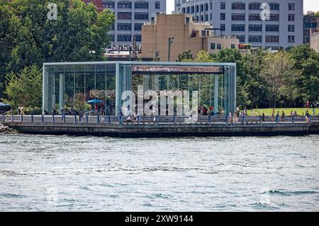 Jane’s Carousel se tient à l’ombre du pont de Brooklyn. L'amusement vitré a été déplacé de Youngstown, Ohio. Vue depuis le ferry East River. Banque D'Images