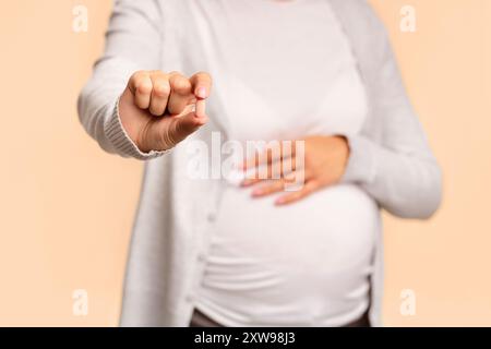 Fille enceinte montrant comp toucher Belly Over White Background, Cropped Banque D'Images