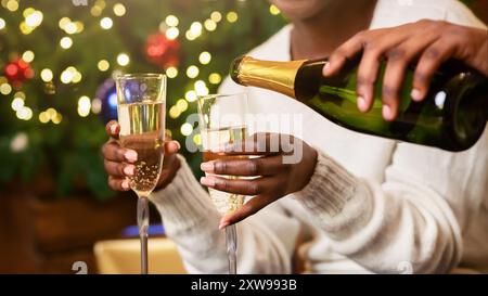 Cheerful black couple drinking champagne près de l'arbre de Noël à la maison Banque D'Images