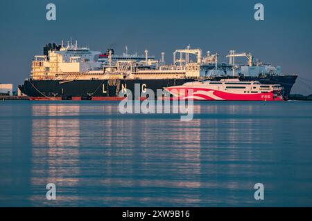 Blick auf die FRS Baltic Faehre und das LNG-Spezialschiff Energos Power , Hintergrund, AM 16.08.2024 im Hafen Mukran in Sassnitz auf der Insel Ruegen. DAS 91 Meter lange Schiff transportiert in der Rekordzeit von 2,5 Stunden Passagiere und Fahrzeuge zwischen Sassnitz, Ruegen, Deutschland, und Trelleborg, Schweden. DAS umstrittene Fluessiggas-terminal, Hintergrund, in Mukran auf Ruegen Hat den Probebetrieb aufgenommen. Betreiberfirma des 300 Meter langen Spezialschiffes ist die Deutsche Regas. Es ist mit Flussigerdgas aus Norwegen beladen und das erste von zwei für das terminal geplanten Regasi Banque D'Images