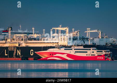 Blick auf die FRS Baltic Faehre und das LNG-Spezialschiff Energos Power , Hintergrund, AM 16.08.2024 im Hafen Mukran in Sassnitz auf der Insel Ruegen. DAS 91 Meter lange Schiff transportiert in der Rekordzeit von 2,5 Stunden Passagiere und Fahrzeuge zwischen Sassnitz, Ruegen, Deutschland, und Trelleborg, Schweden. DAS umstrittene Fluessiggas-terminal, Hintergrund, in Mukran auf Ruegen Hat den Probebetrieb aufgenommen. Betreiberfirma des 300 Meter langen Spezialschiffes ist die Deutsche Regas. Es ist mit Flussigerdgas aus Norwegen beladen und das erste von zwei für das terminal geplanten Regasi Banque D'Images