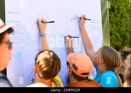 Les jeunes écrivent leurs prières sur un long rouleau de toile au Mladifest 2024 – le festival annuel de la jeunesse à Medjugorje. Banque D'Images