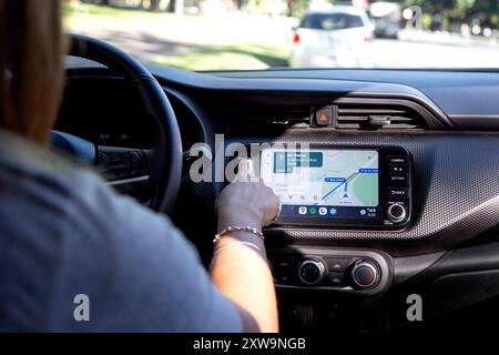 Femme dans une voiture installant gps avant de conduire. Utilisation du système de positionnement global pour la navigation. Toucher l'écran du moniteur avec sa main. Rosario, Argen Banque D'Images