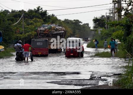 Wattala, Sri Lanka. 18 août 2024. Des personnes et des véhicules traversent les eaux de crue sur une route goudronnée à Wattala, Sri Lanka, le 18 août 2024. Crédit : Gayan Sameera/Xinhua/Alamy Live News Banque D'Images