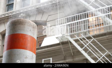 Vapeur évacuée sur New York City Street, cheminée de tubes de vapeur orange. Fumée chaude provenant du tuyau. Système Steam Operations de CON Edison, 5 Fifth avenue Manhattan Midtown architecture. Echelle de feu. Banque D'Images