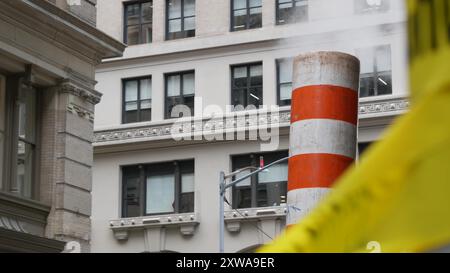 Vapeur évacuée sur New York City Street, cheminée de tubes de vapeur orange. Fumée chaude provenant du tuyau. CON Edison's Steam Operations System, 5 Fifth Avenue, Manhattan Midtown. Ne croisez pas le ruban d'avertissement jaune. Banque D'Images