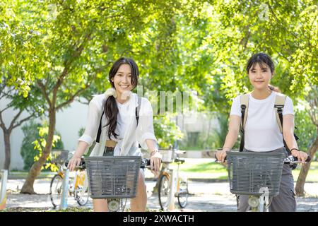 Adolescentes avec des sacs à dos sur des vélos allant à l'école Banque D'Images