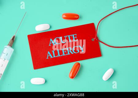 Mots d'ALLERGIE AIGUË sur un carton rouge dans une composition avec des comprimés, des vitamines et une seringue. Banque D'Images