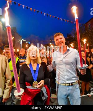 Bridport, Dorset, Royaume-Uni. 18 août 2024. Des centaines de personnes portant des torches flamboyantes prennent part à la procession annuelle aux torches du carnaval de Bridport, de l'hôtel de ville de Bridport à East Beach à West Bay dans le Dorset. La procession de Two Mile était dirigée par la mairesse de Bridport Anne Rickard et le député de West Dorset Edward Morello. Crédit photo : Graham Hunt/Alamy Live News Banque D'Images