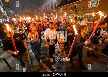 Bridport, Dorset, Royaume-Uni. 18 août 2024. Des centaines de personnes portant des torches flamboyantes participent à la procession annuelle des torches du carnaval de Bridport. La procession de Two Mile a commencé à l'hôtel de ville de Bridport et s'est terminée à East Beach à West Bay dans le Dorset. Crédit photo : Graham Hunt/Alamy Live News Banque D'Images