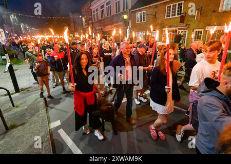 Bridport, Dorset, Royaume-Uni. 18 août 2024. Des centaines de personnes portant des torches flamboyantes participent à la procession annuelle des torches du carnaval de Bridport. La procession de Two Mile a commencé à l'hôtel de ville de Bridport et s'est terminée à East Beach à West Bay dans le Dorset. Crédit photo : Graham Hunt/Alamy Live News Banque D'Images