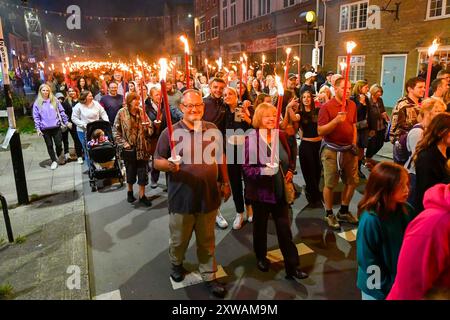 Bridport, Dorset, Royaume-Uni. 18 août 2024. Des centaines de personnes portant des torches flamboyantes participent à la procession annuelle des torches du carnaval de Bridport. La procession de Two Mile a commencé à l'hôtel de ville de Bridport et s'est terminée à East Beach à West Bay dans le Dorset. Crédit photo : Graham Hunt/Alamy Live News Banque D'Images