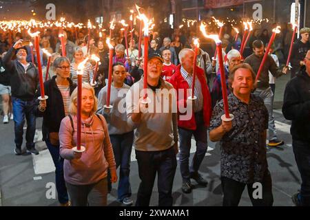 Bridport, Dorset, Royaume-Uni. 18 août 2024. Des centaines de personnes portant des torches flamboyantes participent à la procession annuelle des torches du carnaval de Bridport. La procession de Two Mile a commencé à l'hôtel de ville de Bridport et s'est terminée à East Beach à West Bay dans le Dorset. Crédit photo : Graham Hunt/Alamy Live News Banque D'Images