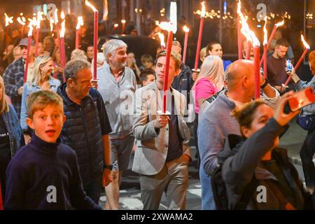 Bridport, Dorset, Royaume-Uni. 18 août 2024. Des centaines de personnes portant des torches flamboyantes participent à la procession annuelle des torches du carnaval de Bridport. La procession de Two Mile a commencé à l'hôtel de ville de Bridport et s'est terminée à East Beach à West Bay dans le Dorset. Crédit photo : Graham Hunt/Alamy Live News Banque D'Images