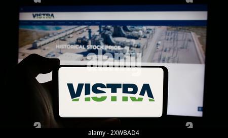 Personne tenant le téléphone portable avec le logo de la société d'énergie américaine Vistra Corp. en face de la page Web de l'entreprise. Concentrez-vous sur l'affichage du téléphone. Banque D'Images